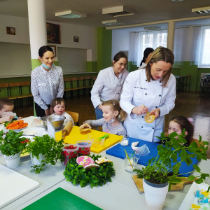 Nauczycielka prezentuje sposób dekoracji ciastek wielkanocnych