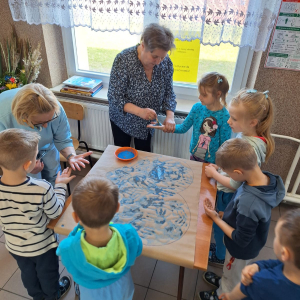 Nauczycielki malują dłonie dzieci na niebiesko