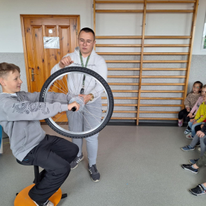 Bartek trzyma w rękach koło od roweru, przygotowuje się do eksperymentu.