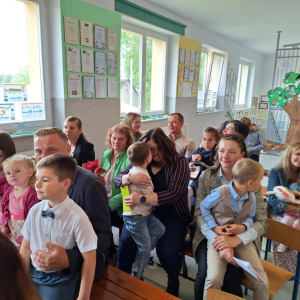 Rodzice uśmiechają się do swoich dzieci siedzących im na kolanach.