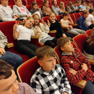 Uczniowie siedzą na widowni.