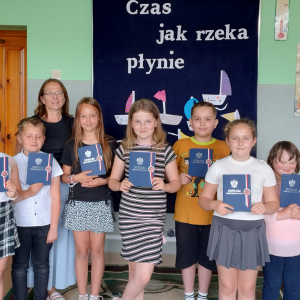 Uczniowie z wychowawczynią stoją przed gazetką " Czas jak rzeka płynie".