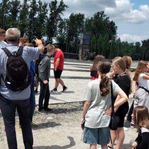Uczniowie klasy VIII słuchają opowiadań przewodnika o historii obozu.