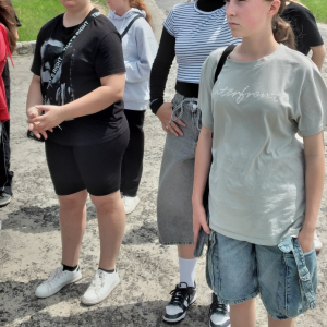 Uczniowie klasy VIII słuchają opowiadań przewodnika o historii obozu.