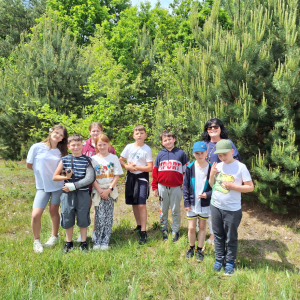 Uczniowie klasy IV wraz z opiekunem pozują do zdjęcia na tle lasu