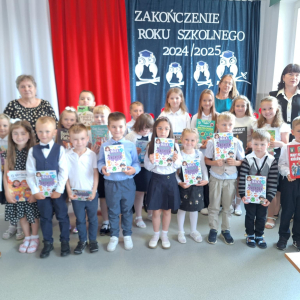 Młodsi uczniowie pozują do zdjęcia z nagrodami