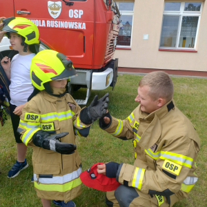 Strażak Jarek rozmawia z uczniem ubranym w mundur strażacki.