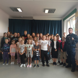 Uczniowie pozują do zdjęcia z policjantem
