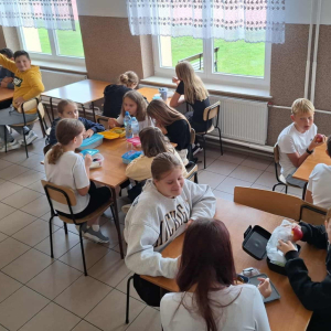 Uczniowie przy stolikach jedzą drugie śniadanie.