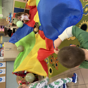 Dzieci bawią się chustą animacyjną w kreatywne zabawy ruchowe. .