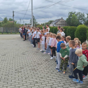 Uczniowie stoją przed szkołą na zbiórce.