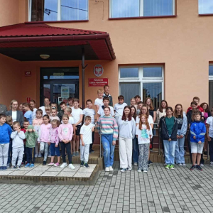 Uczniowie wraz z wychowawcami, dyrekcją i przybyłym gościem stoją na tle budynku szkoły.
