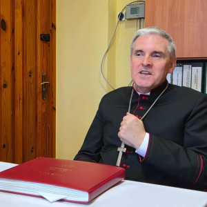 Ksiądz biskup wpisuje się do kroniki szkolnej.