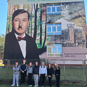 Uczniowie kl. VIII robią sobie pamiątkowe zdjęcie na tle muralu szkoły w Nowej Dębie.