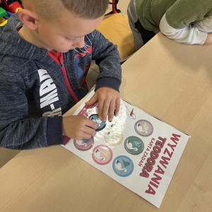 Michał przykleja zdobytą odznakę "Odkrywcy Antarktydy". 