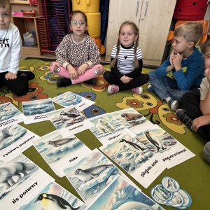 Dzieci uważanie słuchają ciekawostek dotyczących zwierząt zamieszkujących na Antarktydzie.