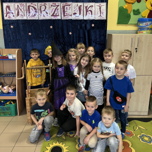  Dzieci pozują na tle kolorowej Andrzejkowej dekoracji pełnej gwiazd.