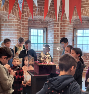 Uczniowie słuchają p. przewodnik, która ciekawie opowiada o kolekcji muzeum