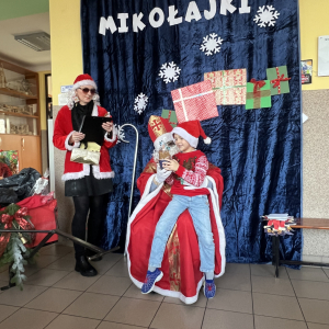 Filip siedzi na kolanach Mikołaja, ciesząc się z prezentu. 