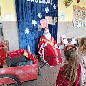 Mikołaj siedzi na swoim miejscu i z uwagą obserwuje dzieci, które przygotowały dla niego krótki występ.