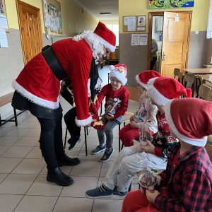 Pani Mikołajowa rozdaje dzieciom cukierki, tworząc radosną i ciepłą atmosferę.