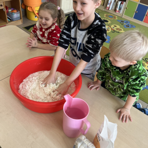 Dzieci przygotowują masę solną, ugniatając składniki, by powstała gotowa do lepienia masa.