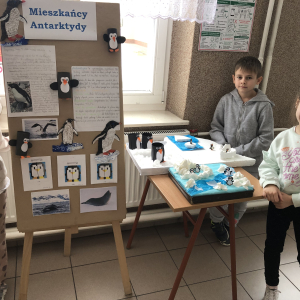 Uczniowie stoją obok gazetki przedstawiającej mieszkańców Antarktydy.