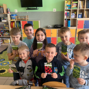 Dzieci z zainteresowaniem oglądają i prezentują nasiona, z których wyrosną rośliny.