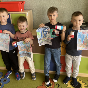 Dzieci dumnie prezentują swoje rysunki państw i kolorowe flagi.