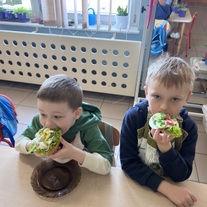 Dzieci siedzą razem i jedzą swoje kanapki. 