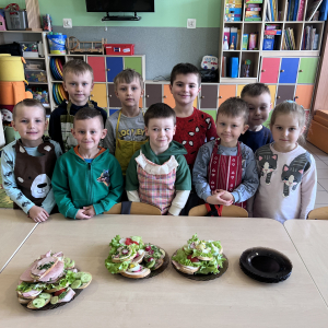 Dzieci pozują do zdjęcia, prezentując zrobione własnoręcznie kanapki.