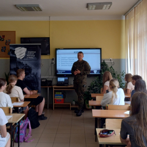  Uczniowie siedzą i słuchają informacji promujących wojsko.