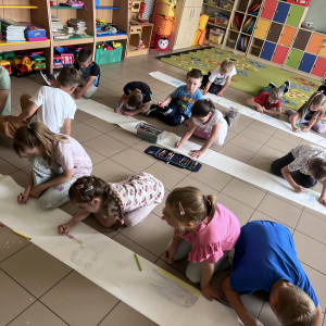 Dzieci malują swoje marzenia na dużych arkuszach papieru, rozwijając kreatywność i wyobraźnię.