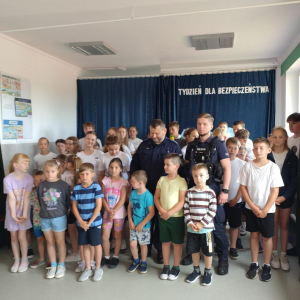 Dzieci pozują do grupowego zdęcia z policjantami po spotkaniu w ramach „Tygodnia dla bezpieczeństwa”